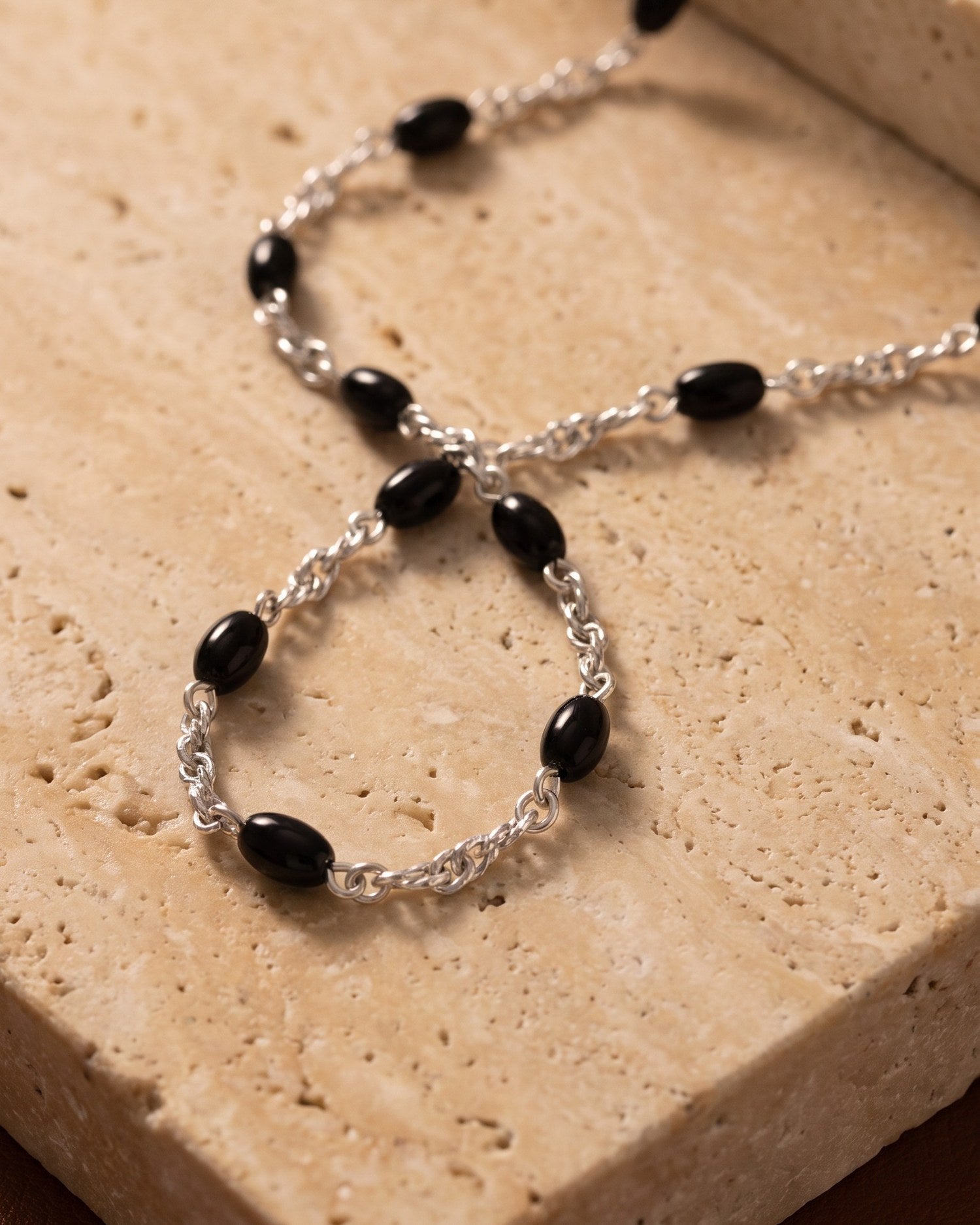 Dusk Chain aus 925 Sterlingsilber mit Onyx-Perlen auf Travertin